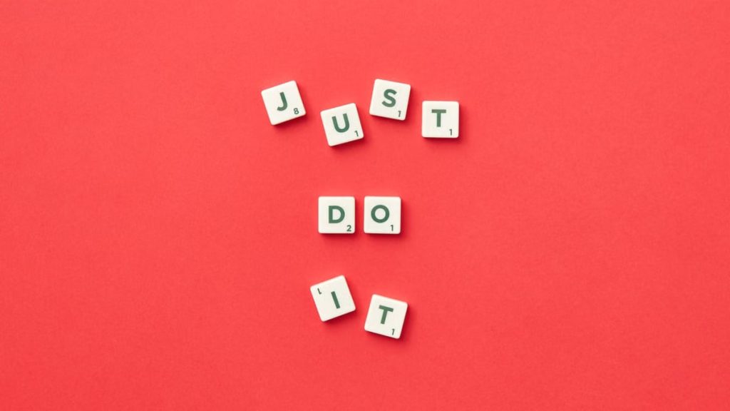 Motivational phrase 'Just Do It' spelled with Scrabble letters on a red background.